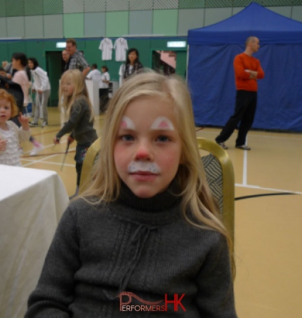 A face painter draw a rabbit face paint for a girl at a corporate Easter event at Hong Kong football club. 