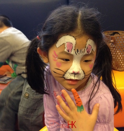 Hong Kong professional face painter paint a creative Easter bunny face paint with a carrot finger paint at a kids Easter function