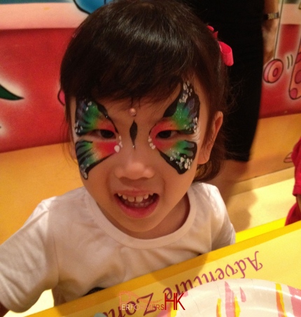 Hong Kong great face painter draw a beautiful butterfly for a little girl at a children birthday party