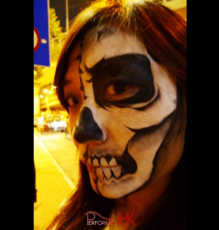 A female face painter draw a black and white skull face paint to join a Halloween event in HK 