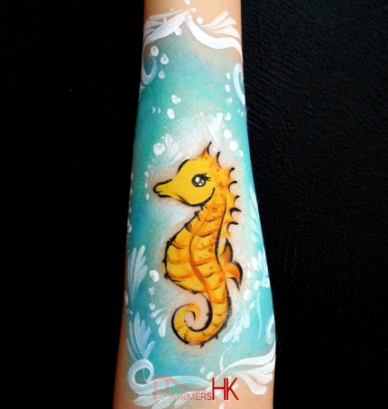 A Hong Kong face painter drew a sea horse arm paint for a under the sea themed event .