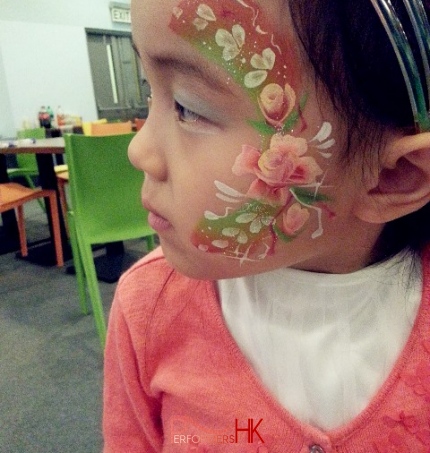 Face painter draw a fancy flower face paint for a little girl at a Hong Kong Xmas party.