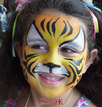 A little girl is very happy with the professional yellow and white lion face paint by a HK face painter she met at a school fair.