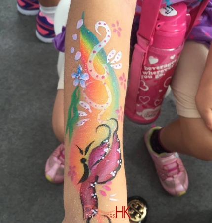 Hong Kong face painter draw a rainbow and butterfly painting on a children hand at a party