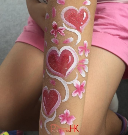 Face painter draw a Heart and flower hand paint with red , white and pink at a Hong Kong corporate event