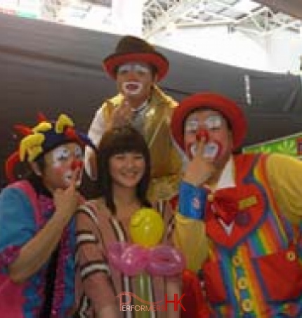 Tony and other clowns poses with a female guest holding her balloon 