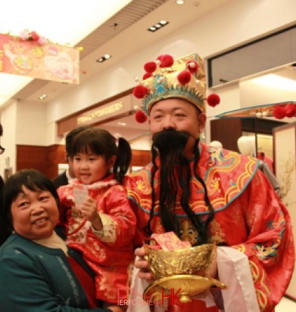 Performer in Choi Sun costume taking picture with an old lady and little girl at a HK shopping mall event