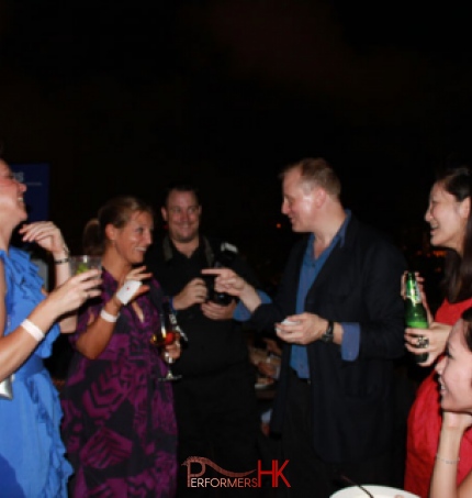 Hong Kong roving magician performing card magic trick to the lady in purple dress who holding a card at a corporate cocktails event 