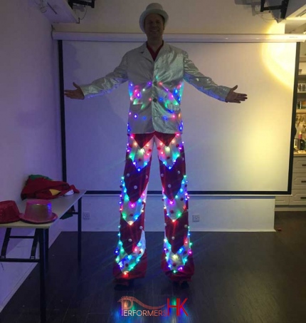 Stiltwalker in a LED costume with sliver jacket taking picture in Hong Kong