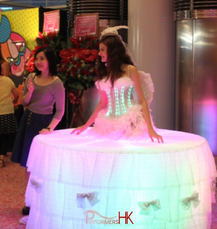 Female Model dressed as a white living table with LEDs having her picture taken 