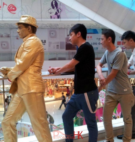 golden statue standing with 3 visitors in a shopping mall 