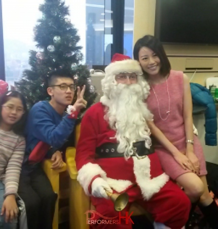 Santa with a lady and two kids taking picture in front of a Christmas tree at a HK Xmas event