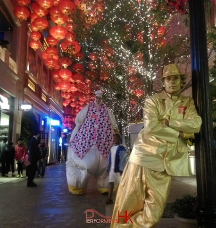 Golden statue leaning on lamp post with Giant Easter Bunny standing background