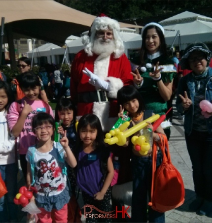 martin santa with santa girl kimmy at an event for children at repulse bay hong kong, kids have balloons and santa and santa girl is smiling