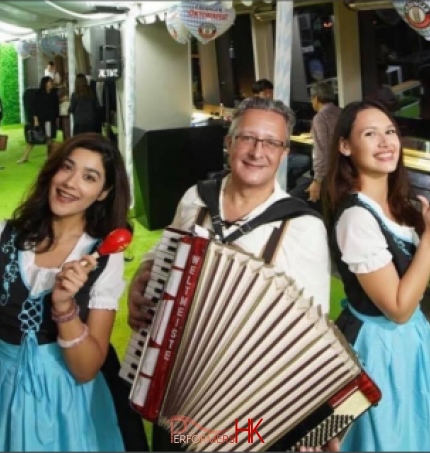 Solo accordionist playing music with 2 models wearing traditional german beer girl costume