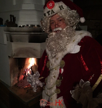 Chinese Santa Mario by the fire place staying warm in maroon colored santa suit