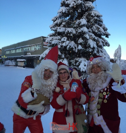 Standing in front of christmas tree with other santa, chinese santa mario is happy and his friend is also happy with finnish local women in tow